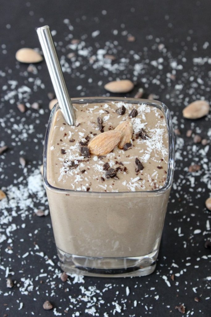 Short glass with chocolate smoothie, sprinkled with coconut and chocolate